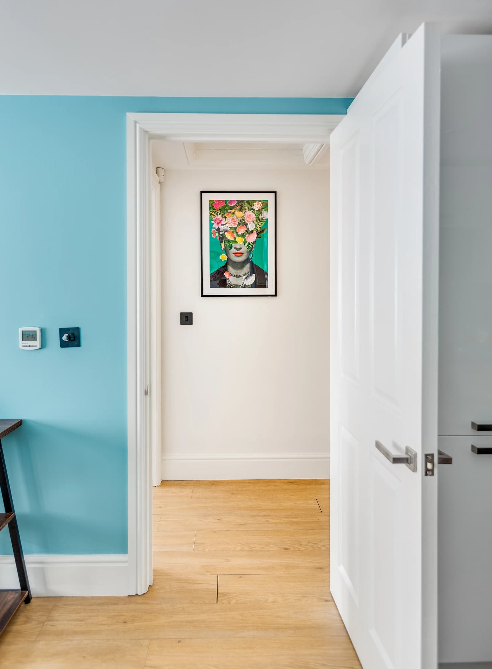 Hallway with colourful artwork and view through to kitchen at Station Road Flat 52a, Egham