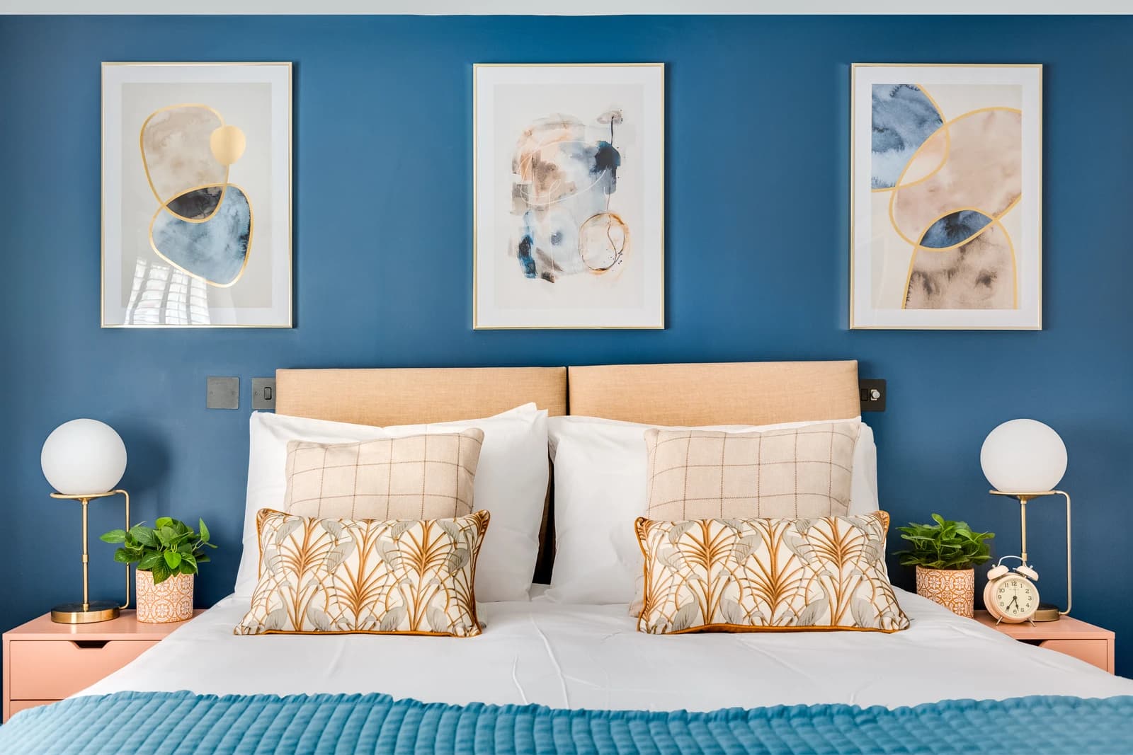 King-size bed with beige headboard, yellow cushions and navy wall at Station Road apartment