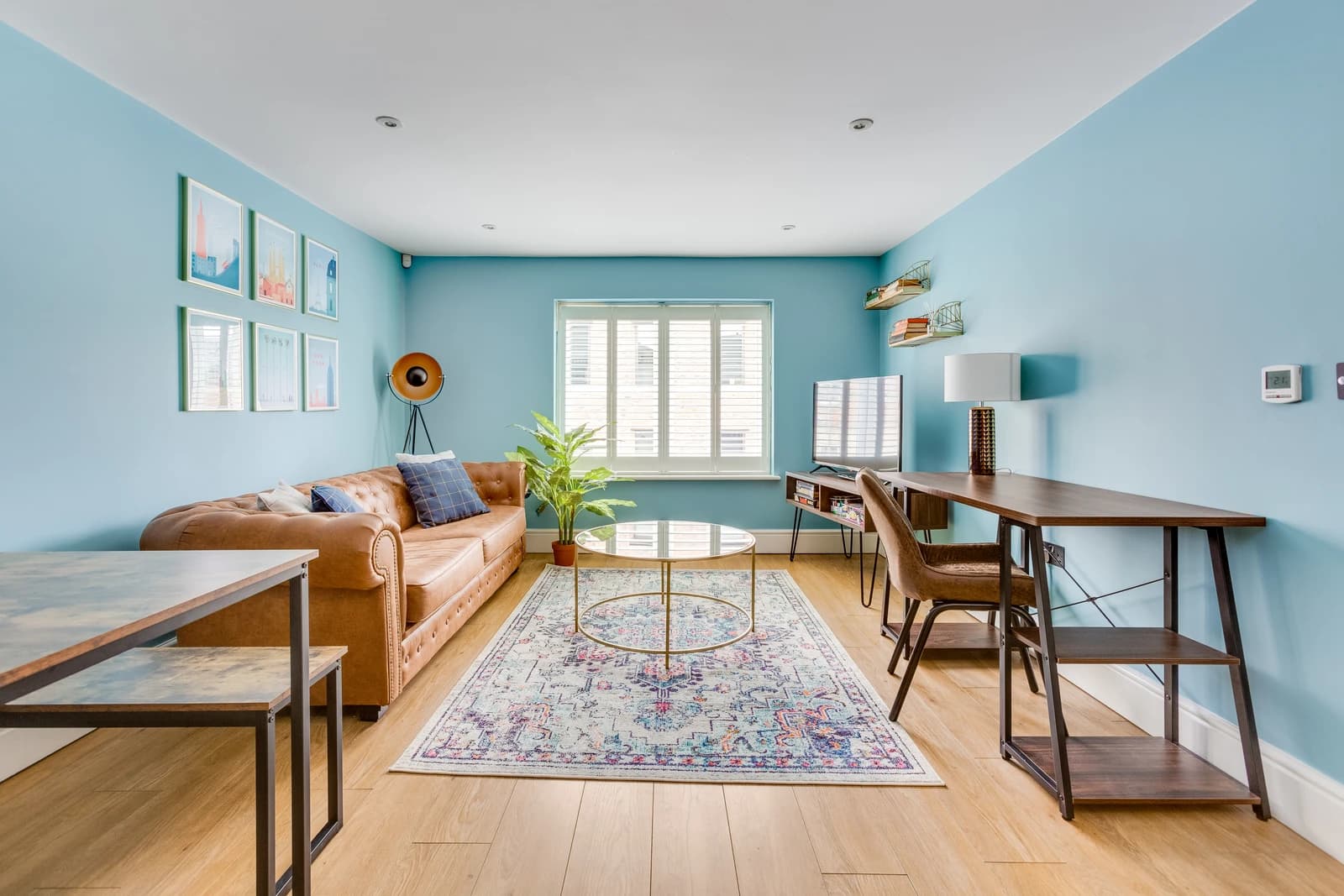 Living and dining area with patterned rug and blue accent wall at Station Road apartment, Egham
