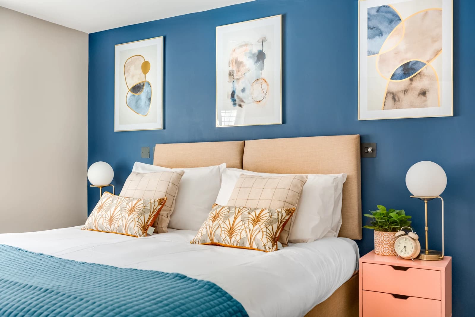 Double bedroom with navy feature wall and modern artwork at Station Road Flat 52a, Egham