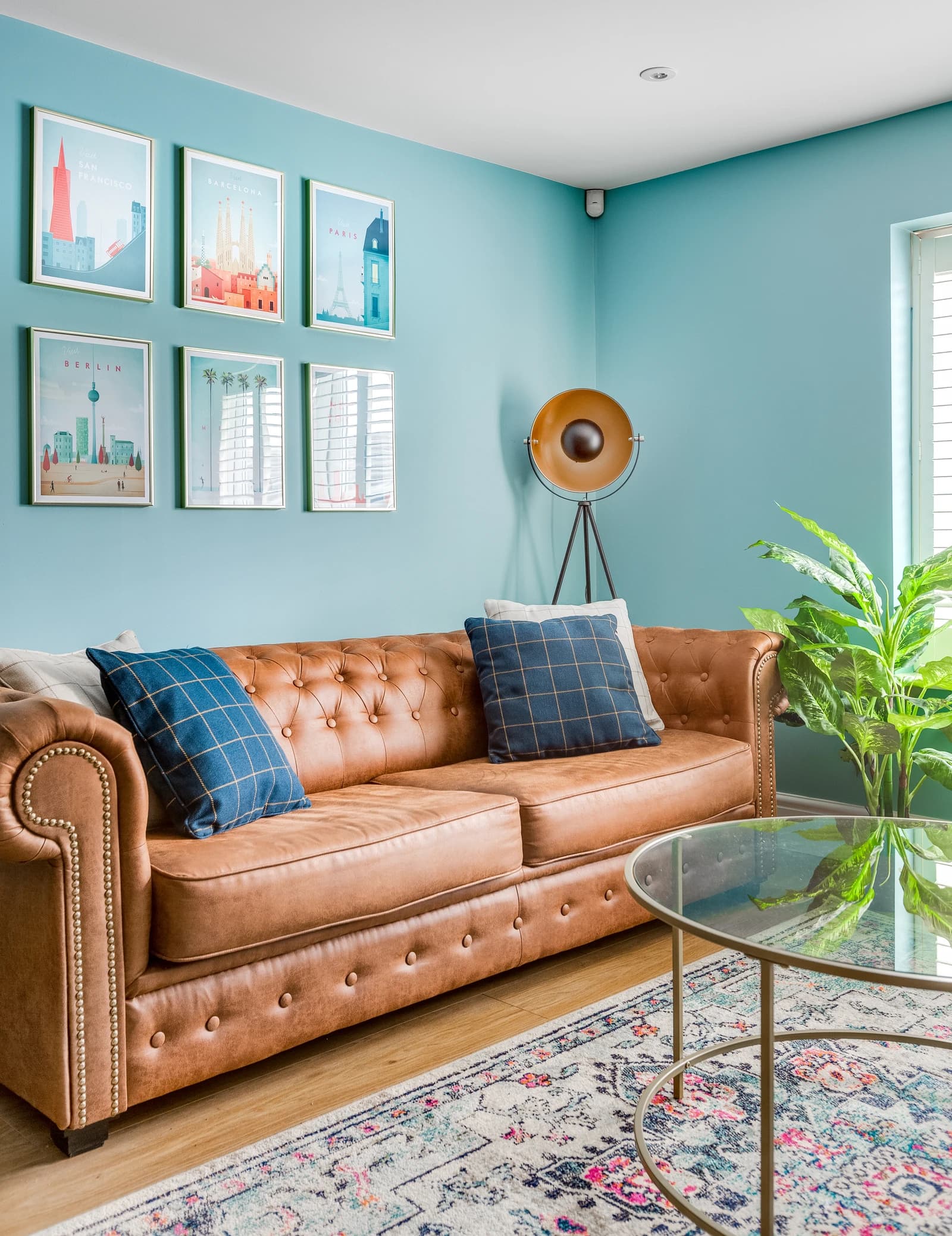 Living room with tan leather sofa, blue cushions and floor lamp at Station Road Flat 52a, Egham