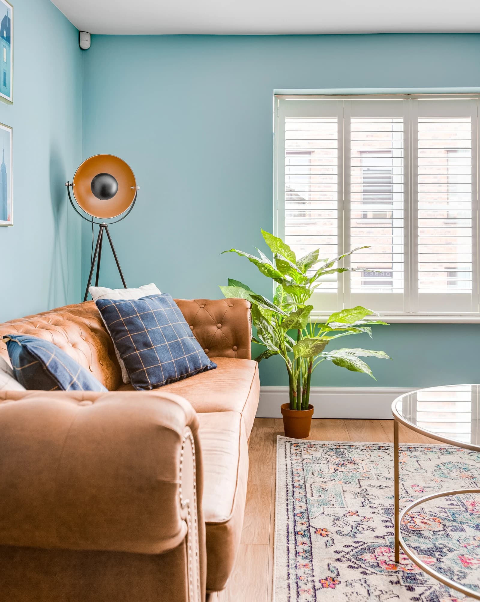 Tan Chesterfield sofa with blue cushions and indoor plants at Station Road serviced apartment