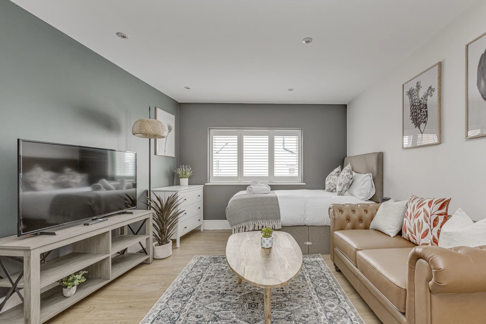 Open-plan living and dining area with leather sofa, dining table and wooden flooring at Boon House, Egham