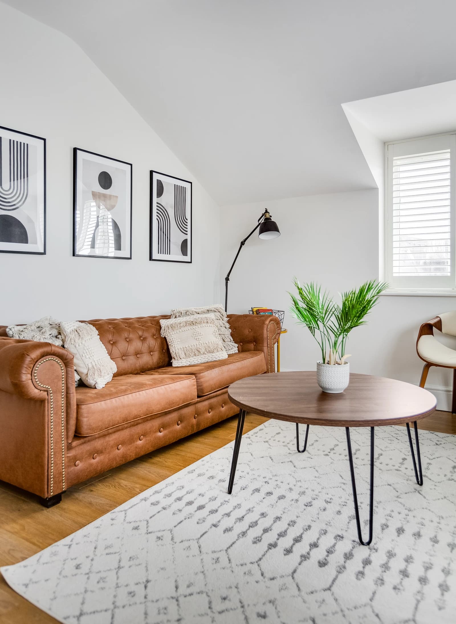 Tan Chesterfield sofa with cushions, plants and modern artwork at Boon House Flat 4