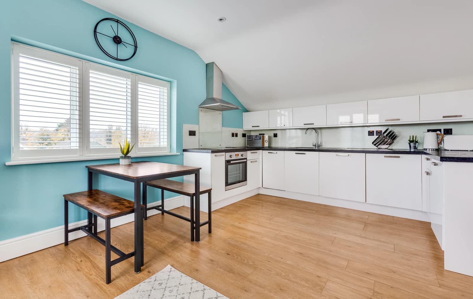Kitchen and dining area with wooden flooring and blue feature wall at Boon House Flat 4, Egham