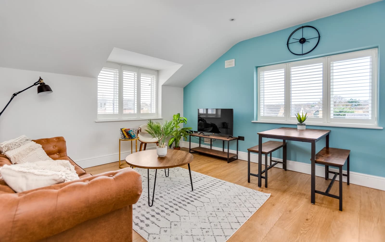 Open-plan living and dining area with tan sofa and blue feature wall at Boon House Flat 4, Egham