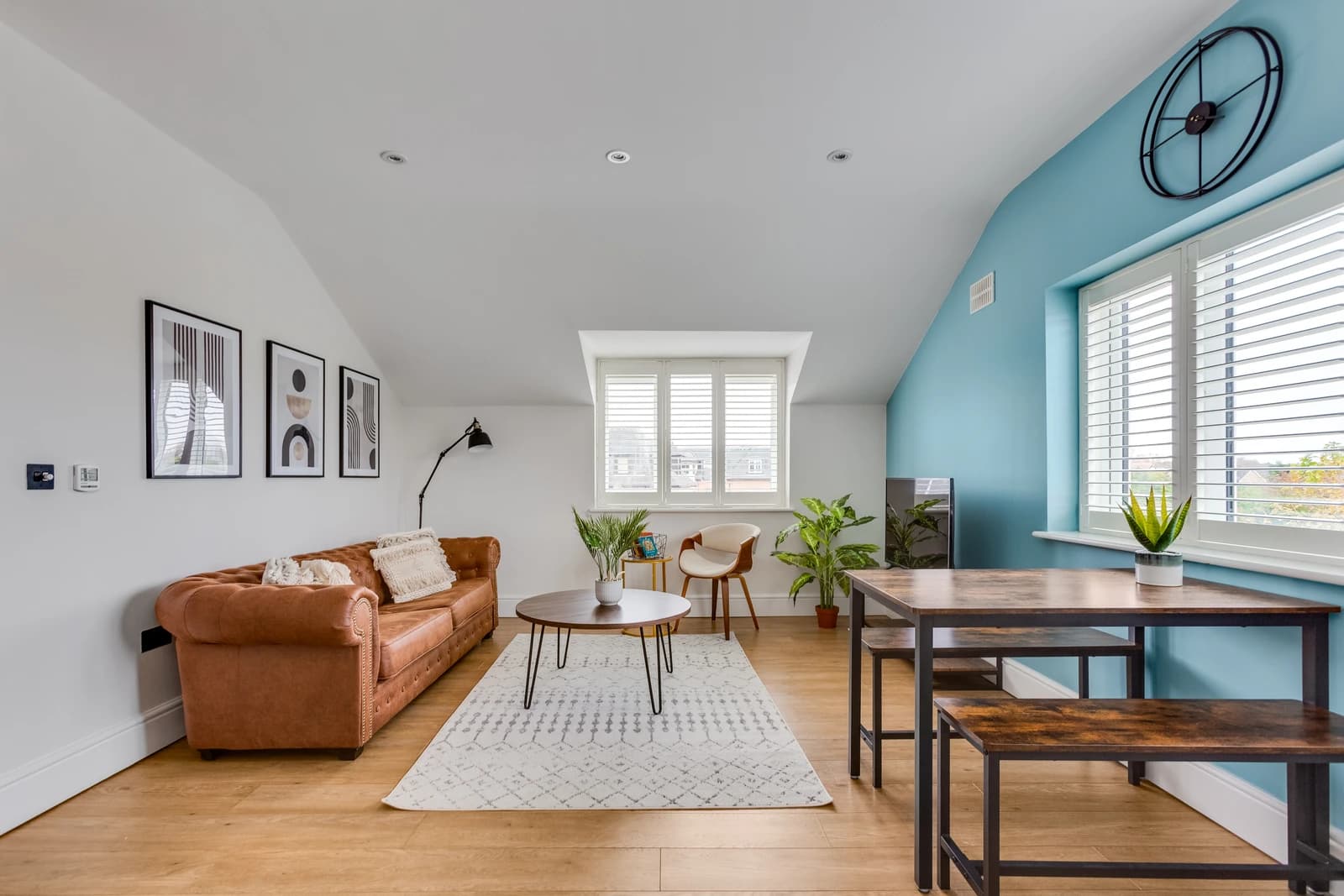 Living and dining area with tan sofa, black dining set and blue wall at Boon House, Egham