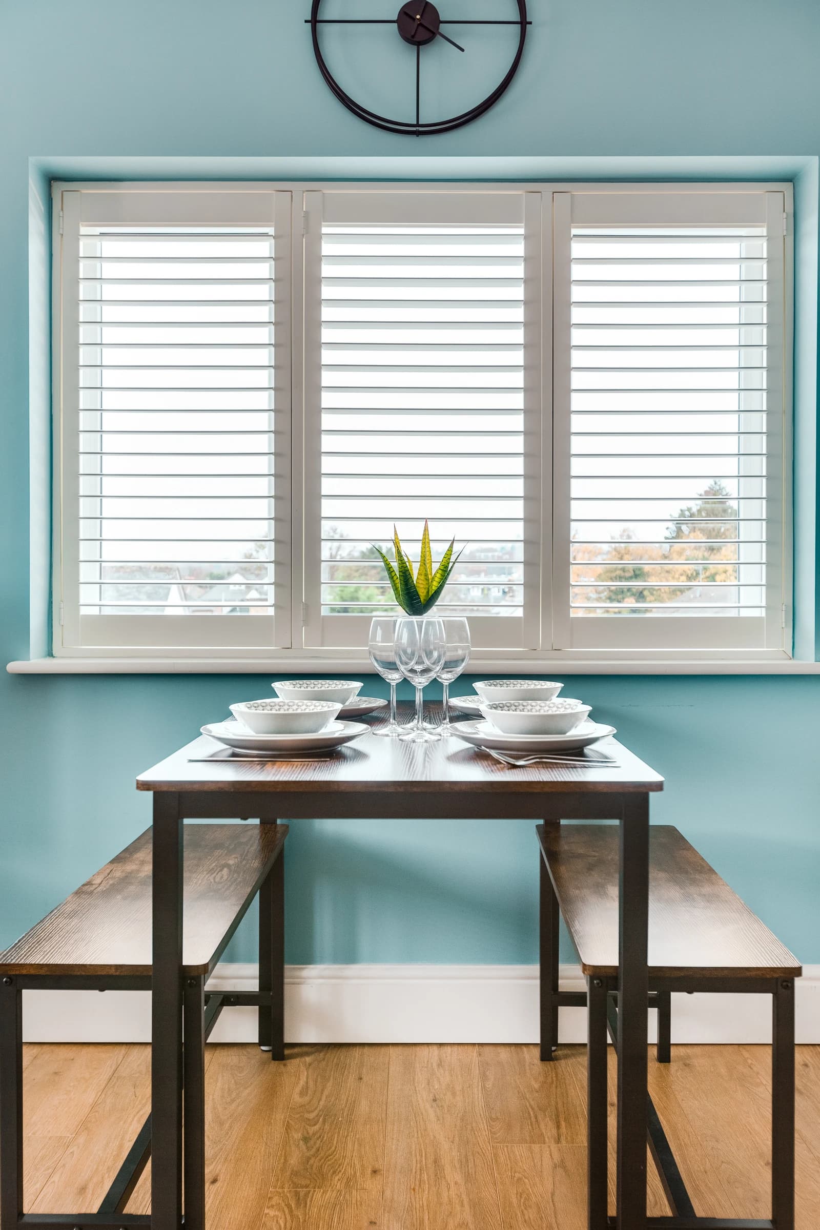 Dining table set for four with wine glasses and blue accent wall at Boon House Flat 4