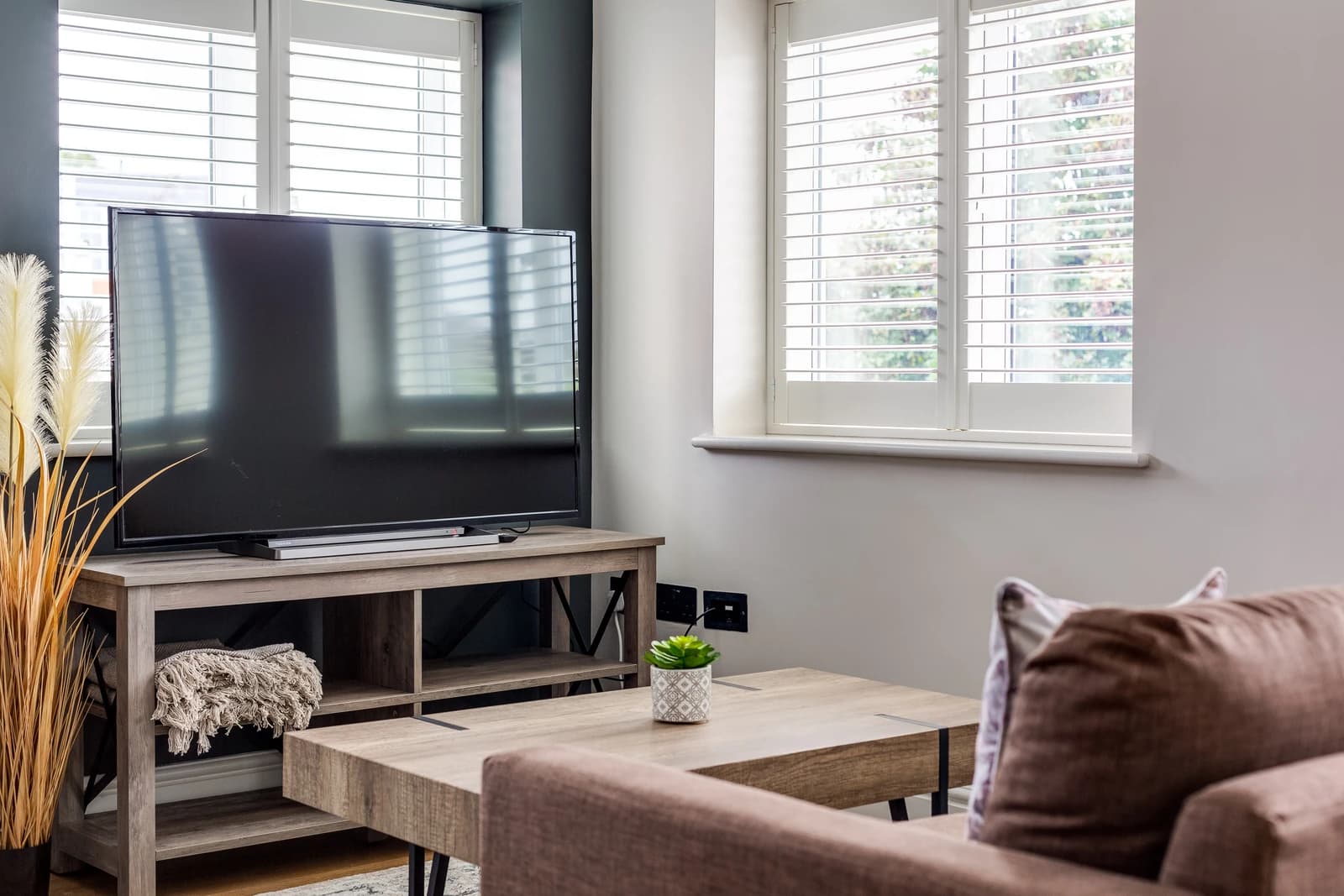 Cosy living room with smart TV, brown sofa and dried pampas grass at Boon House, Egham