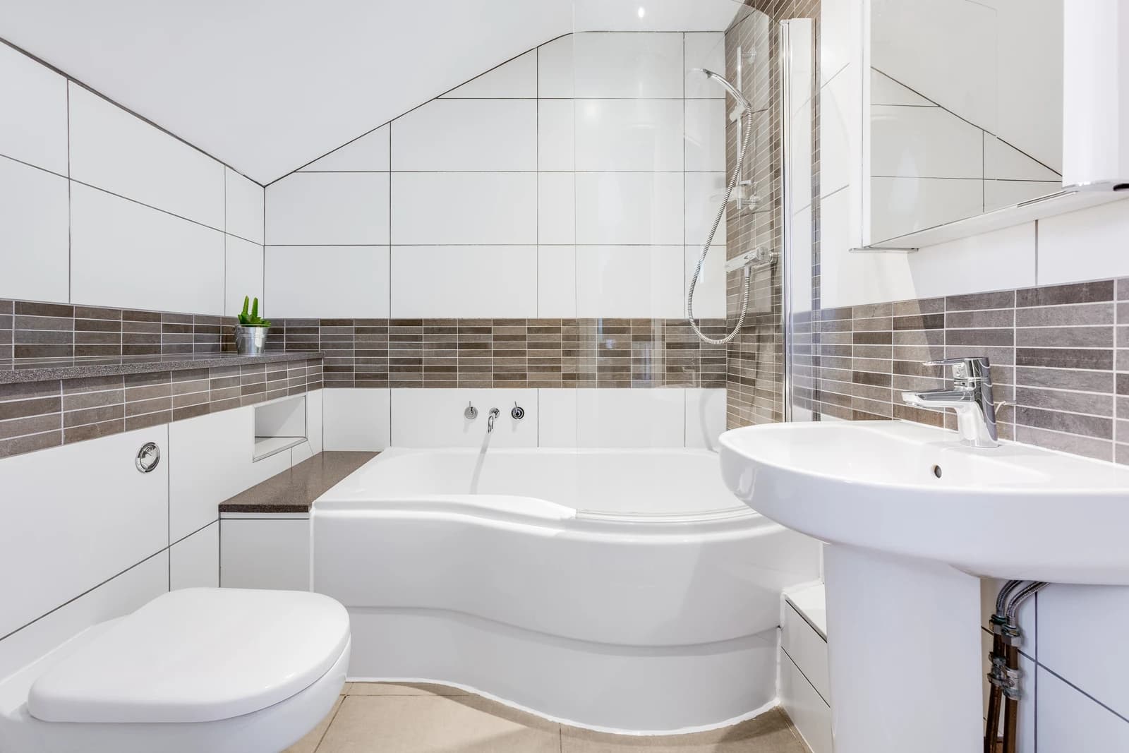 Bathroom with bath, shower screen and grey tiles at Boon House Flat 3, Egham