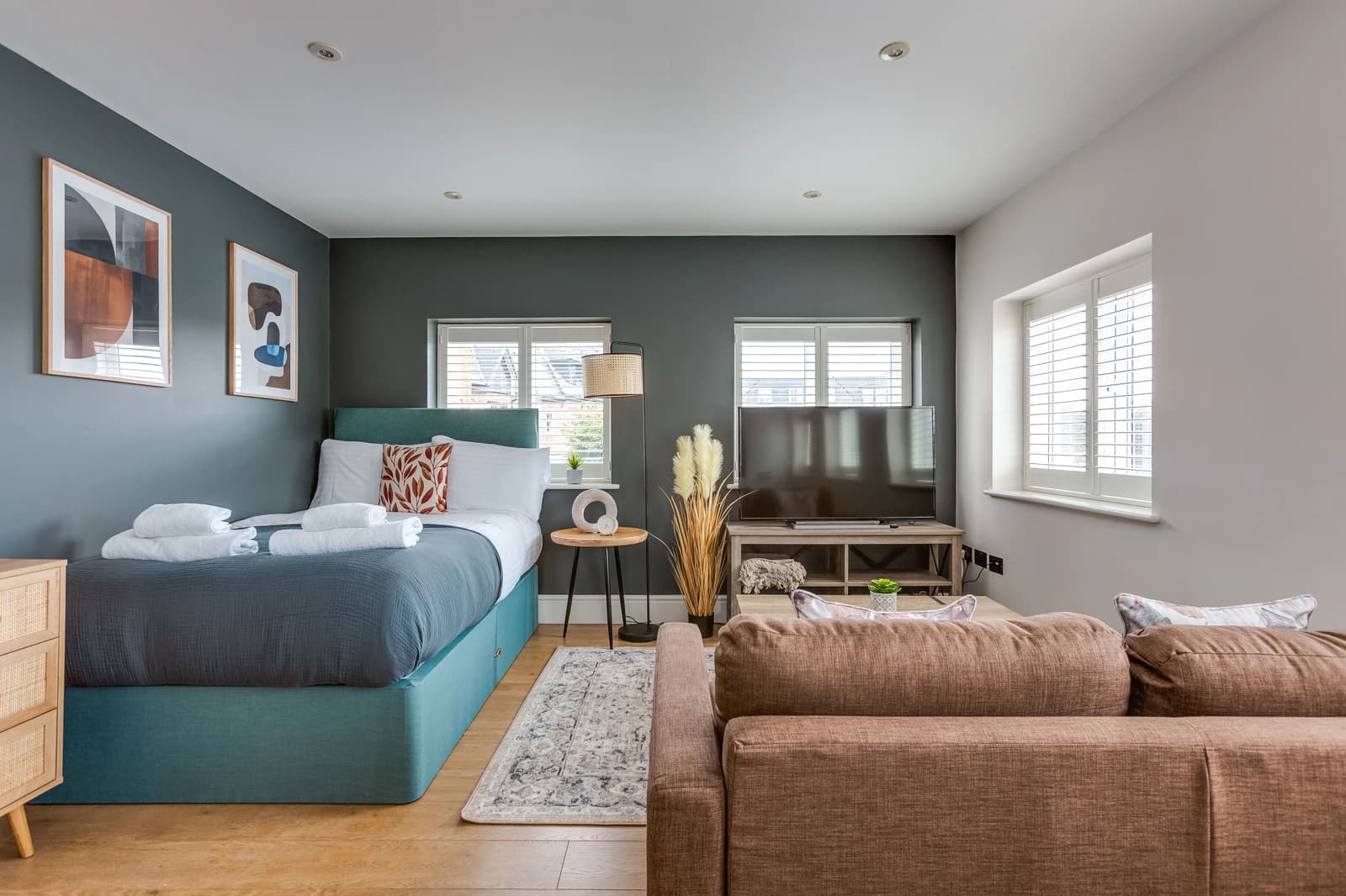 Open-plan living and dining area with teal sofa bed and kitchen at Boon House, Egham
