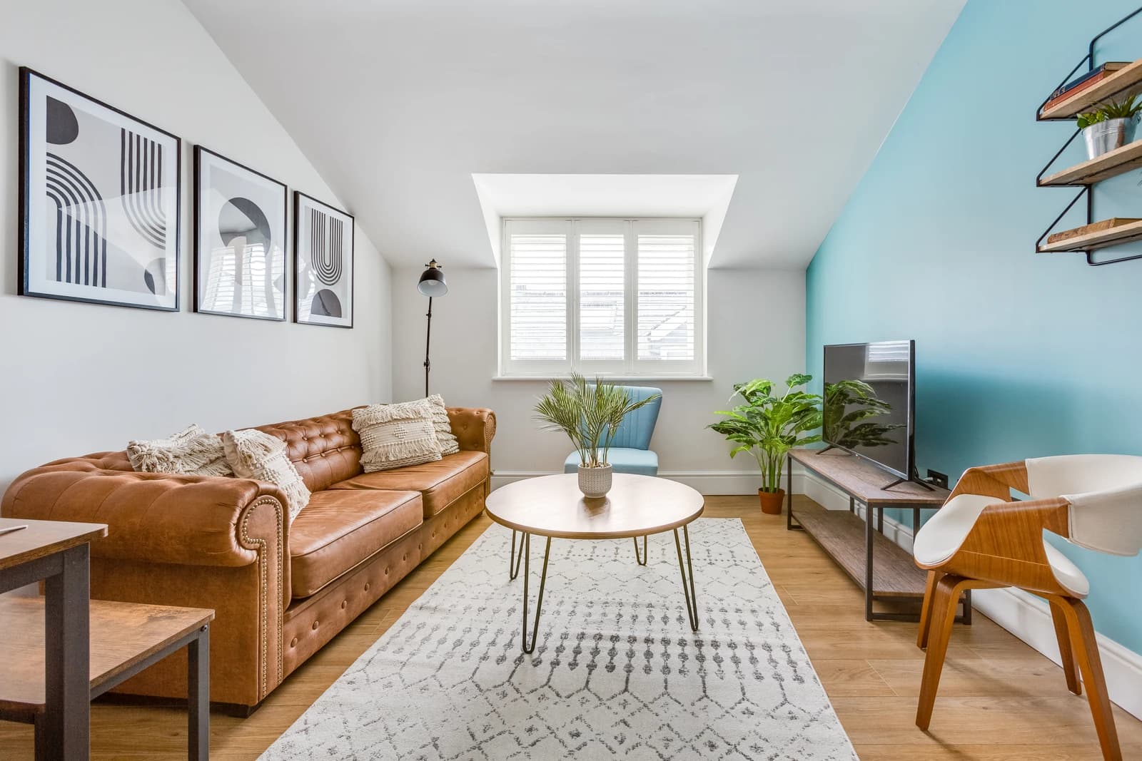Tan leather sofa with plants and modern artwork in the living area at Boon House Flat 3