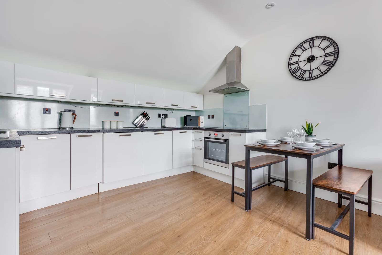White modern kitchen with integrated appliances and wooden flooring at Boon House Flat 3, Egham