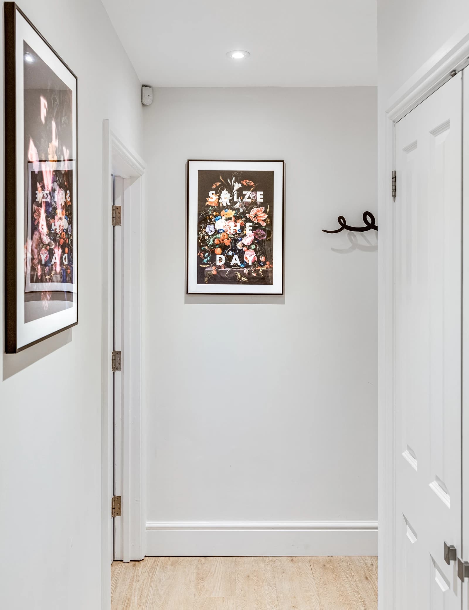 Hallway with framed artwork and wall-mounted coat hooks at Boon House, Egham