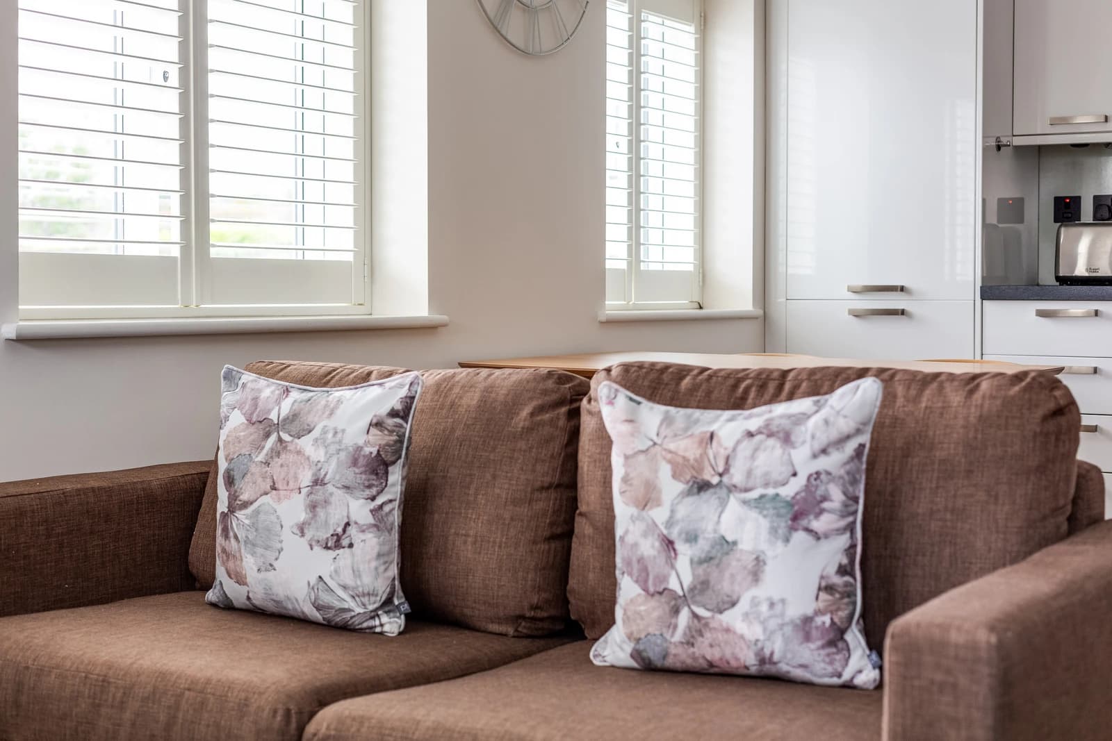 Brown sofa with floral cushions and teal bed in the living area at Boon House Flat 2
