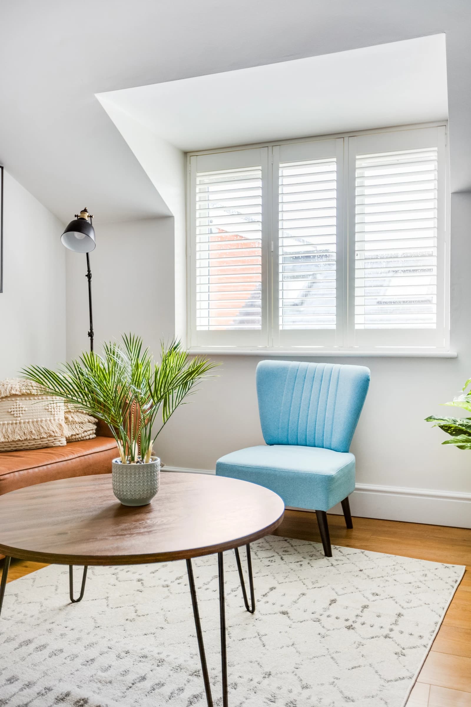 Living area with blue accent chair, plants and natural light at Boon House serviced apartment