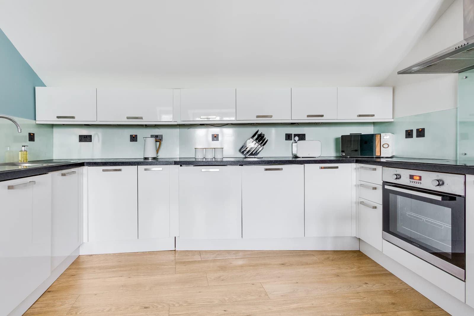 Kitchen with white cabinets, electric cooker and breakfast bar at Boon House, Egham