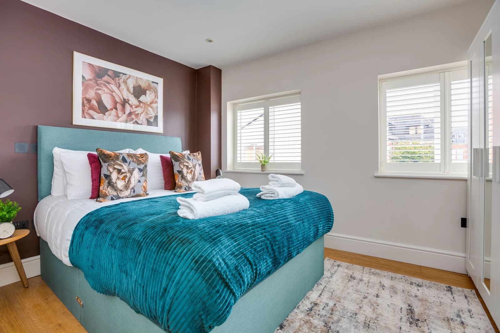 Bedroom with teal bedding, floral artwork and bedside lamp at Boon House Flat 2